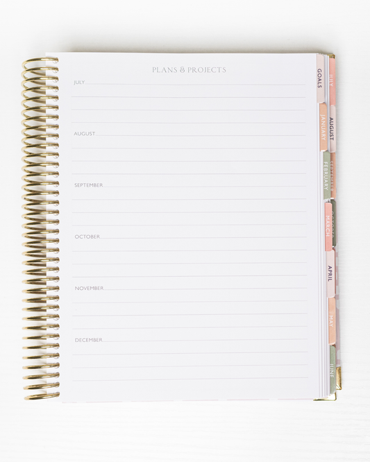 Spiral-bound planner with a white cover and gold spiral binding on a white background